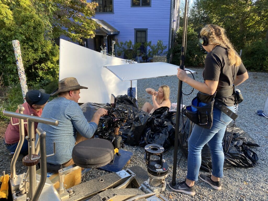 Raven Angeline Whisnant, actor and producer, sits in a pile of garbage bags, surrounded by members of the Biters and Bleeders crew.
